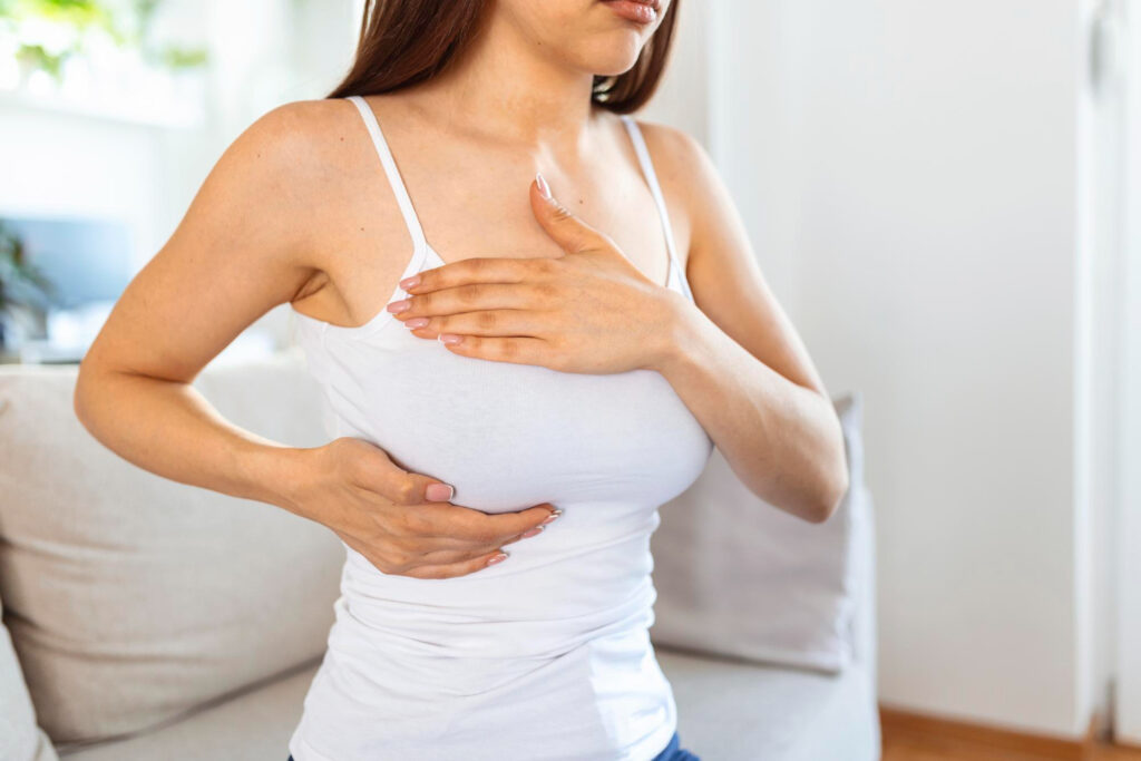 young woman palpating breast that she is concerned about breast cancer